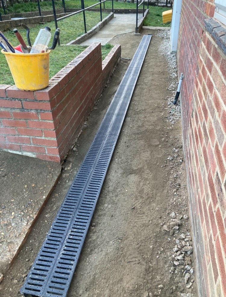 Channel drain installed alongside a brick wall
